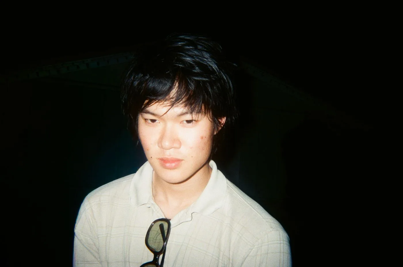 Portrait of Damien Nguyễn in a white collared shirt, lit by direct flash