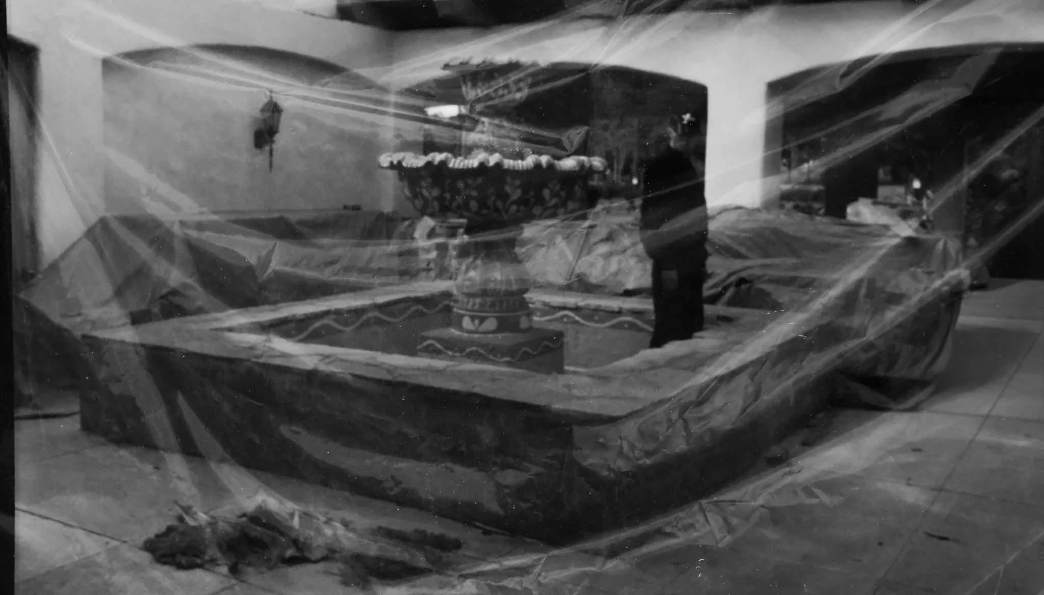 Black-and-white double exposure of an interior draped in plastic sheeting