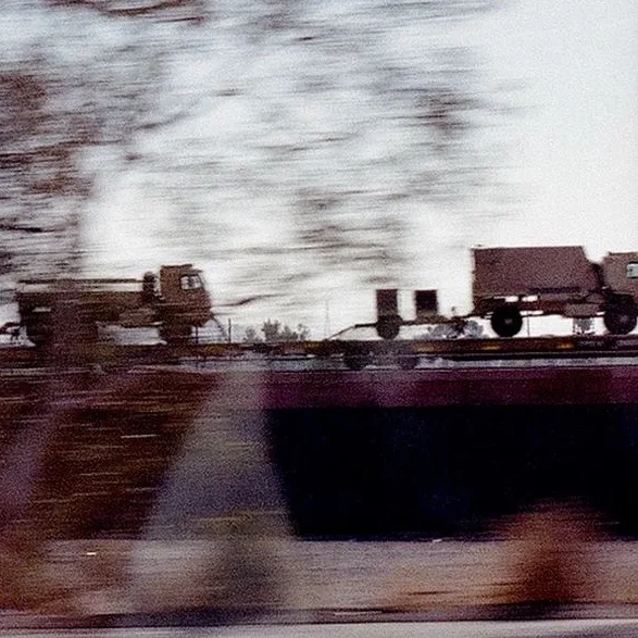 Military trucks on a freeway overpass in motion blur, shot on film from a moving car