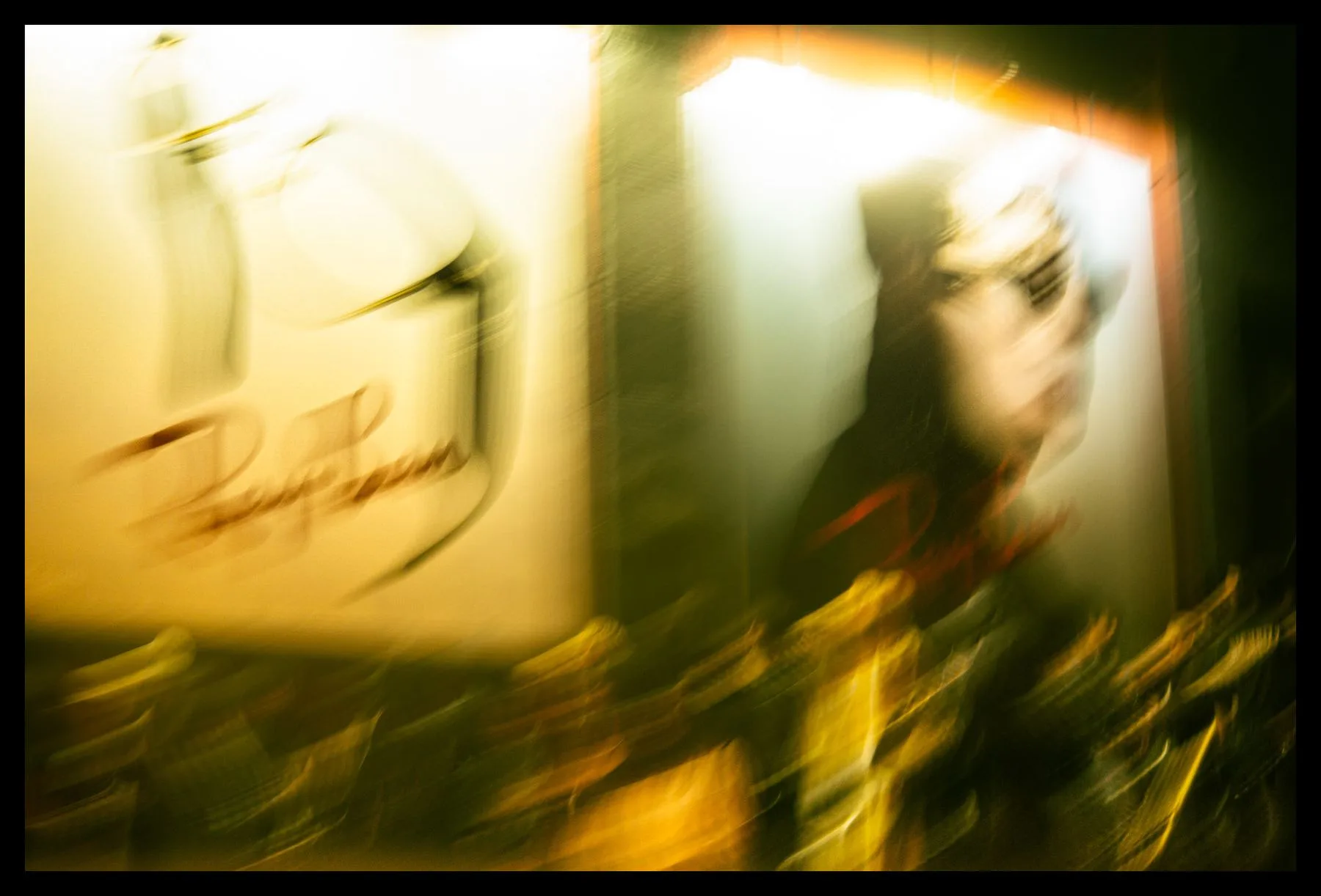 Blurred night frame of posters and gold lights through a shop window
