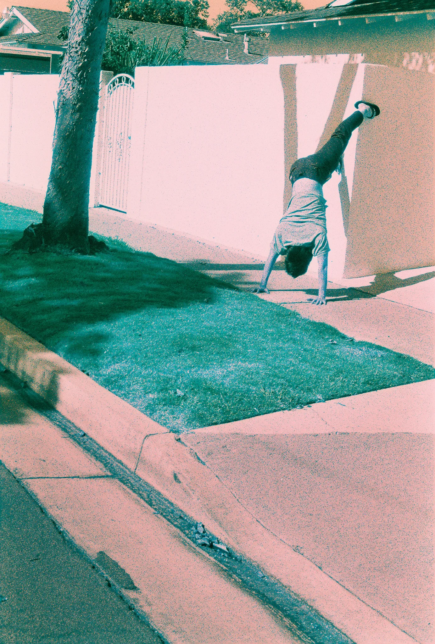 Person captured mid-cartwheel against a suburban wall and lawn, rendered in a teal-and-pink duotone treatment