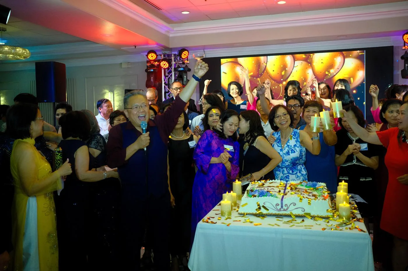 Crowd raising glasses around a cake at a banquet celebration