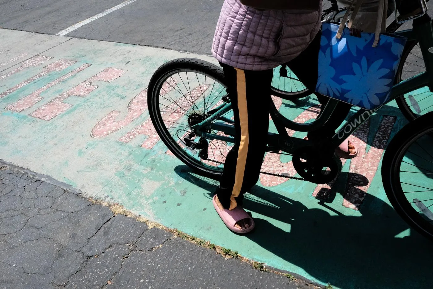 Bicycle wheels and pink slippers over a faded green painted bike lane