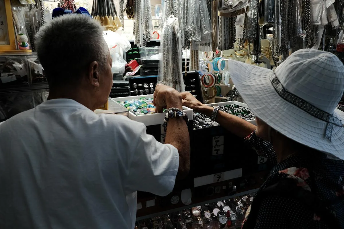 Shopper in a white sun hat trying on a bracelet at a jade jewelry counter