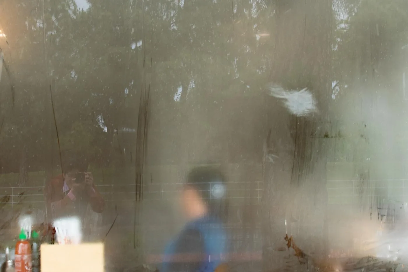 Figure in blue seen through a steamed, paint-smeared kitchen window