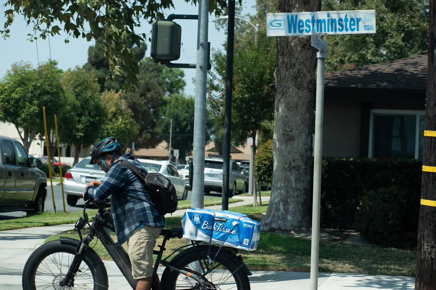 Cyclist with a case of water on the rack pausing under the Westminster street sign