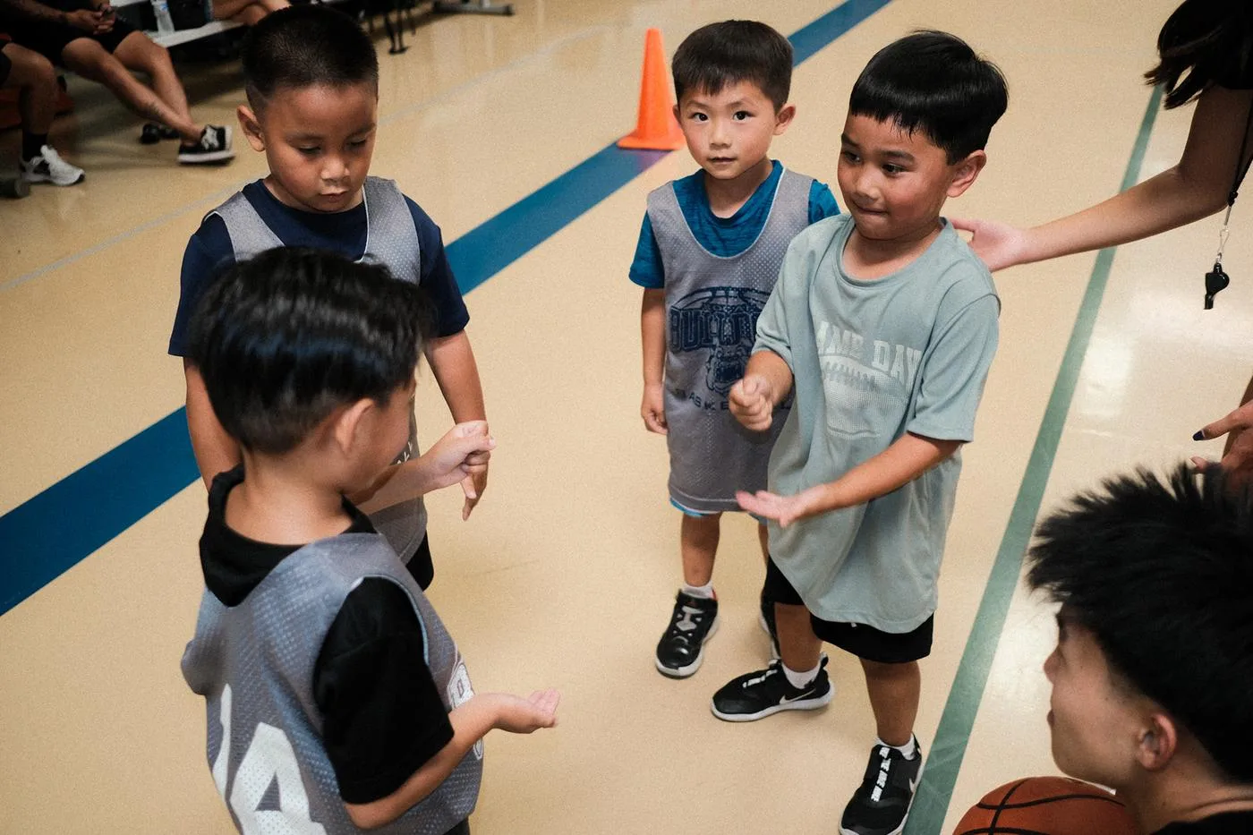 Young players talking at center court, a coach's hand reaching in
