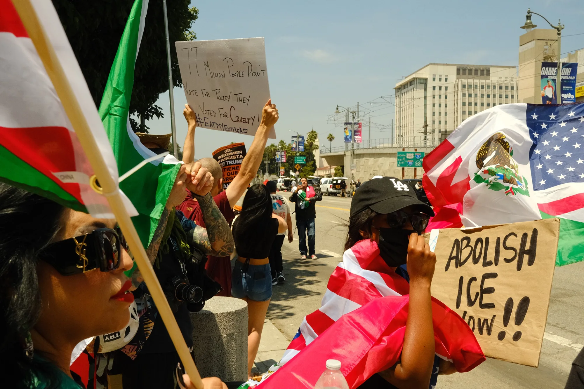 Marchers with Mexican flags and an 'Abolish ICE Now' sign moving down a Los Angeles boulevard