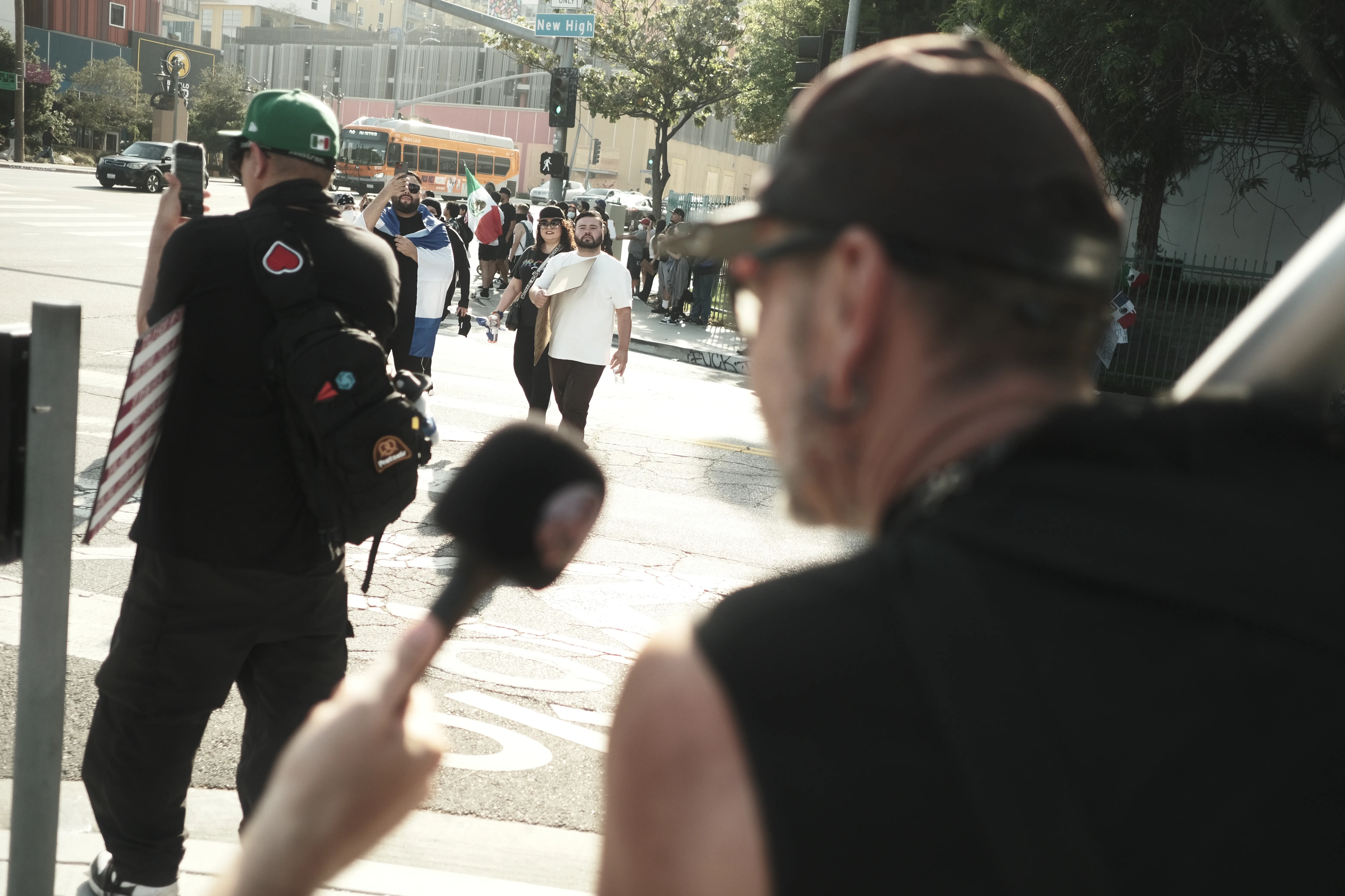 Street corner with a camera operator filming marchers crossing at an intersection