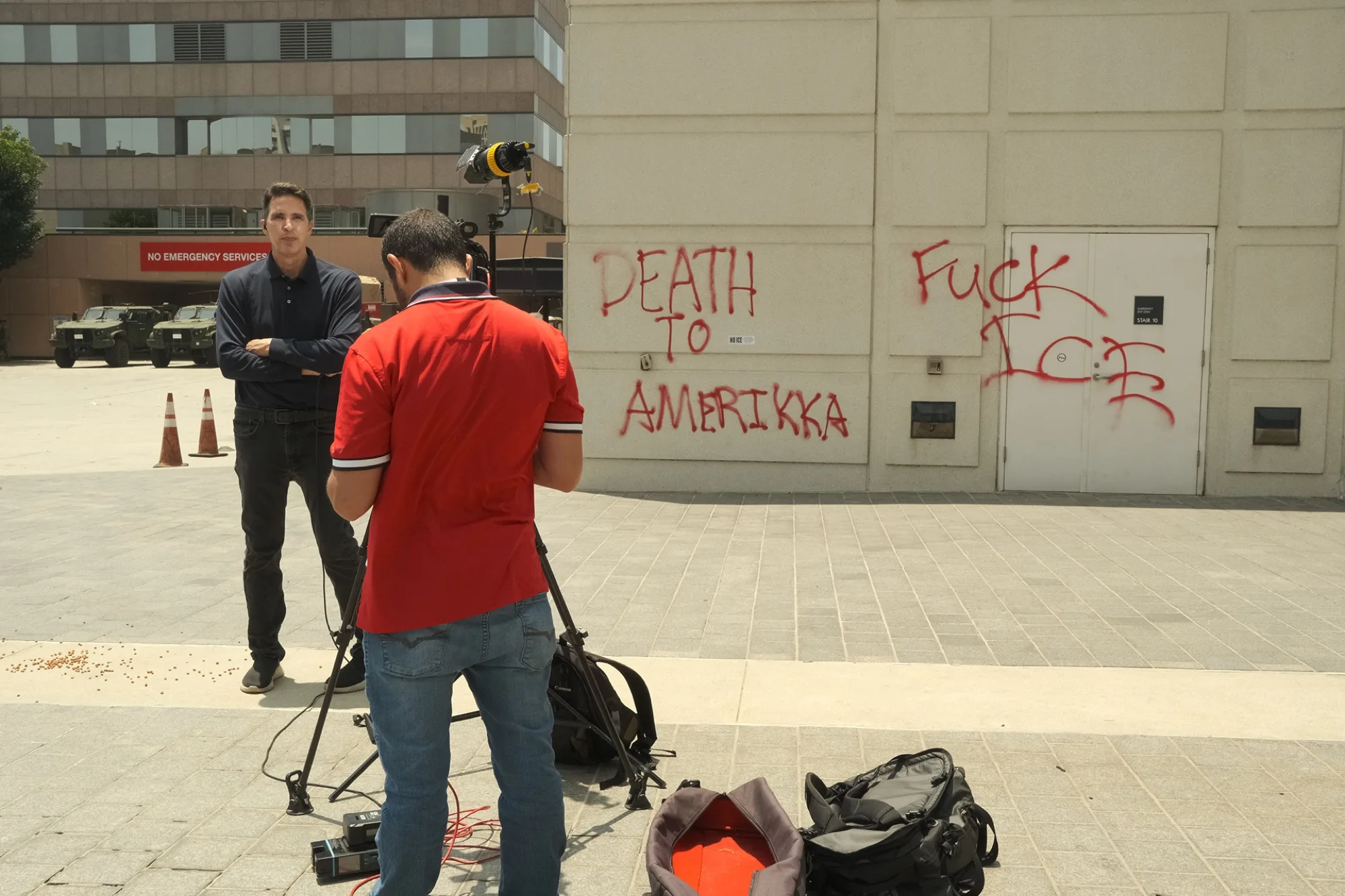 News reporter being filmed in front of a graffiti-covered wall after a protest