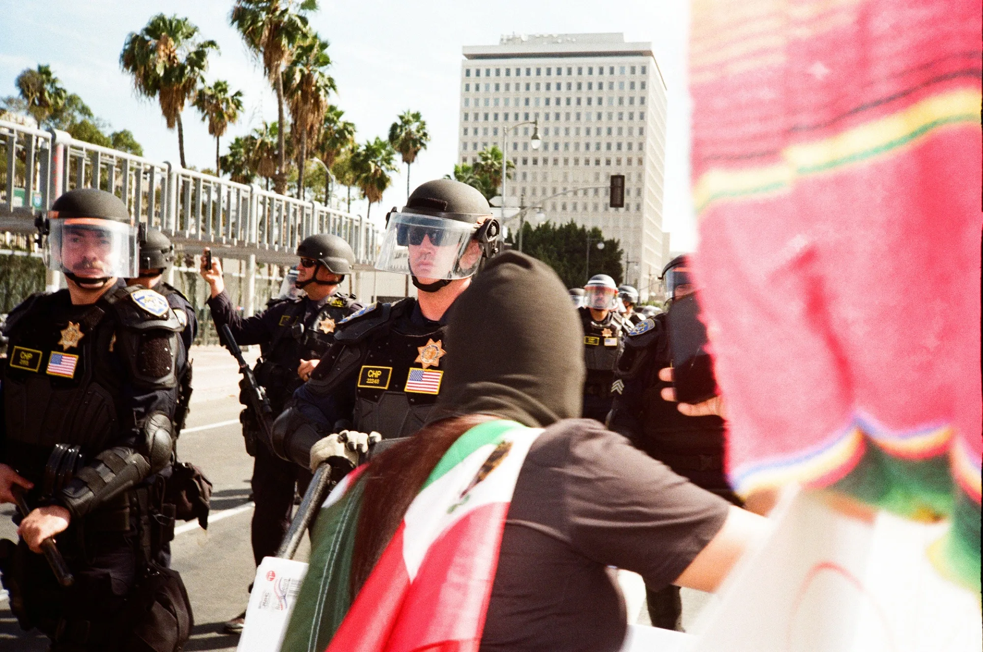 View past a red serape of sheriff's deputies in riot gear outside the county courthouse, on film